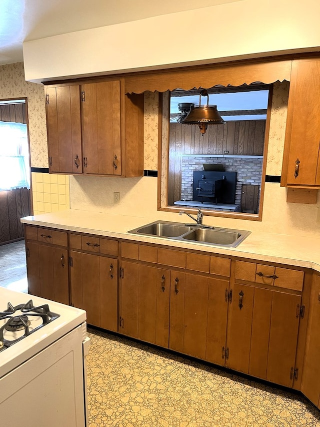 kitchen featuring a sink, wallpapered walls, light countertops, light floors, and white gas range