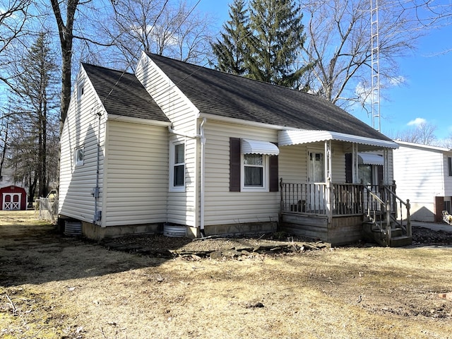 view of front of property featuring an outdoor structure, a storage shed, roof with shingles, and dirt driveway