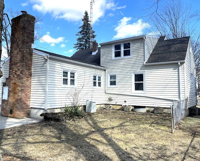 back of property featuring a shingled roof and a chimney