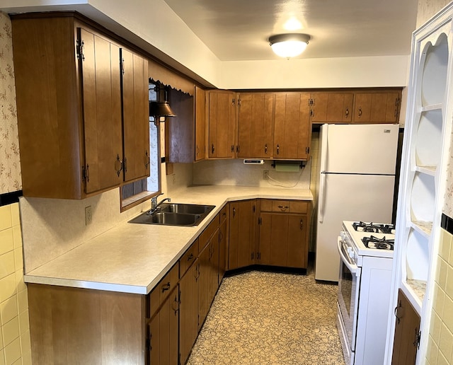 kitchen featuring light floors, light countertops, brown cabinetry, white appliances, and a sink