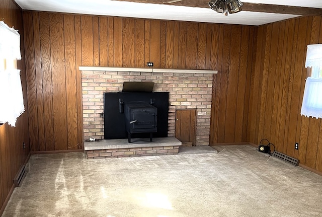 unfurnished living room with visible vents, wood walls, and a wood stove