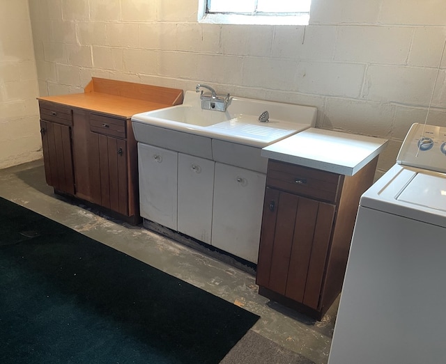 laundry room featuring a sink, washer / dryer, concrete block wall, and laundry area