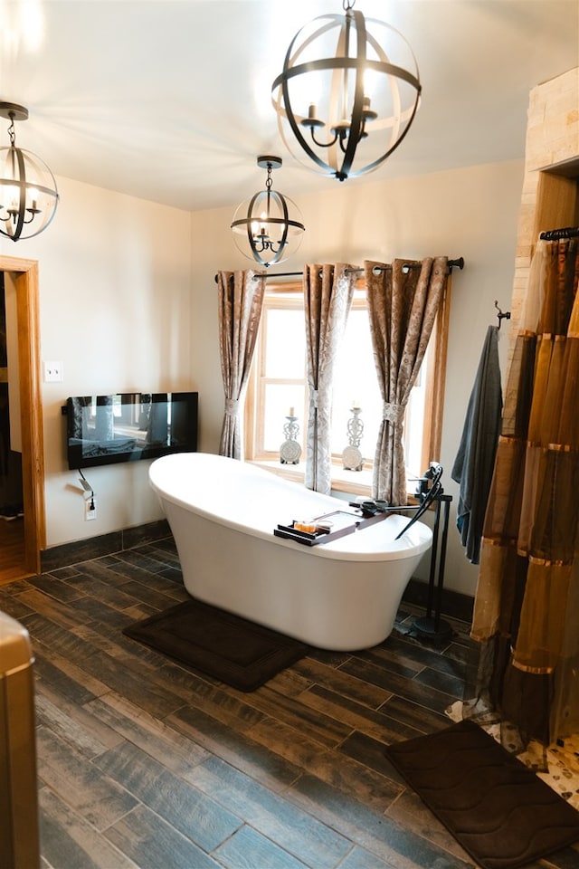 bathroom featuring a freestanding tub, a notable chandelier, and wood finished floors