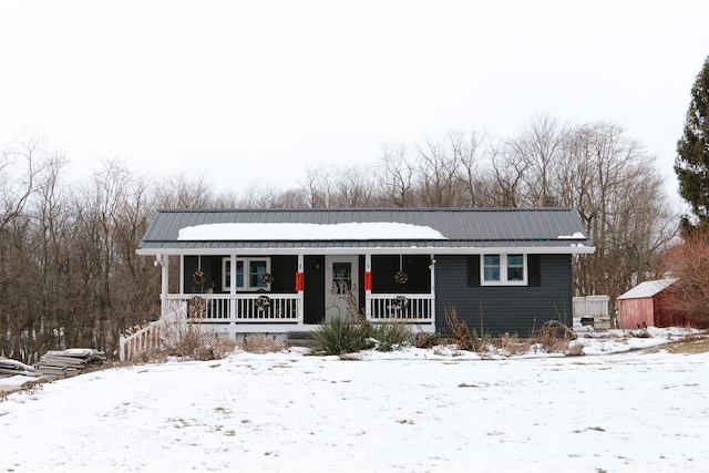 ranch-style house with metal roof, a porch, and an outbuilding