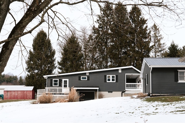 view of front facade with an outbuilding, metal roof, a storage unit, and covered porch