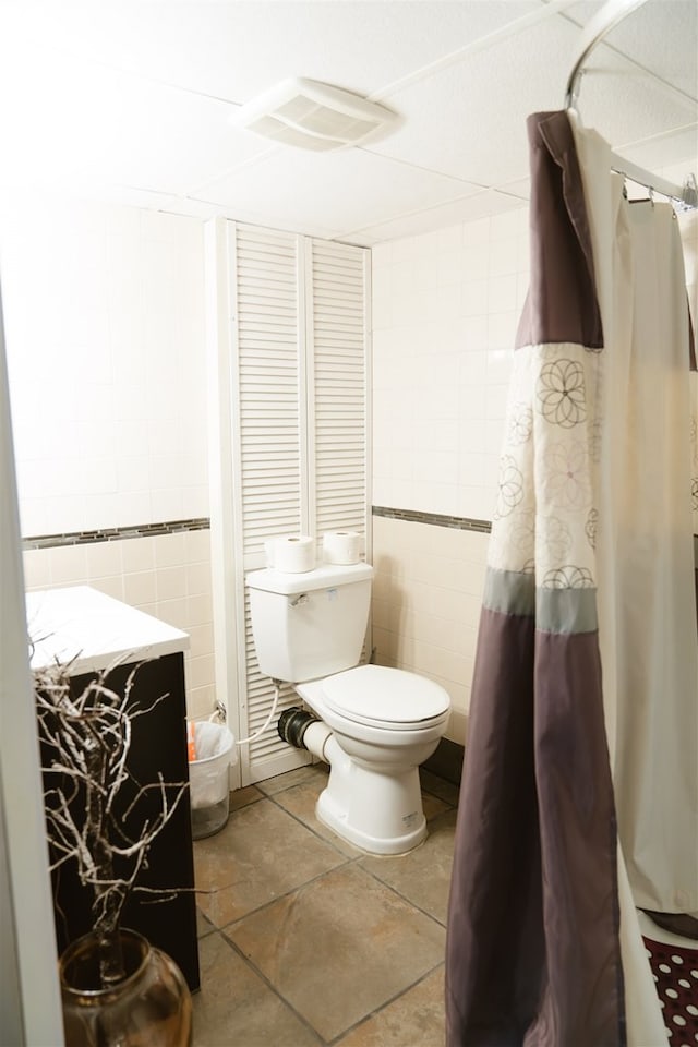 bathroom featuring visible vents, toilet, tile patterned flooring, and tile walls