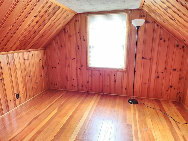 bonus room featuring hardwood / wood-style floors, wood walls, and lofted ceiling