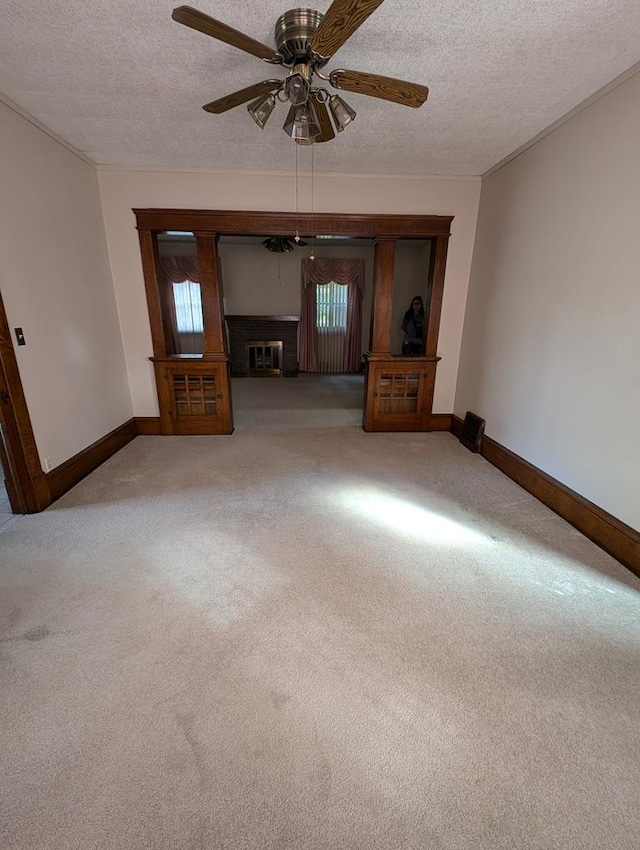 unfurnished living room featuring carpet flooring, a wealth of natural light, ceiling fan, and a textured ceiling