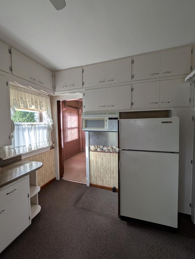 kitchen featuring white cabinetry, white appliances, and dark carpet