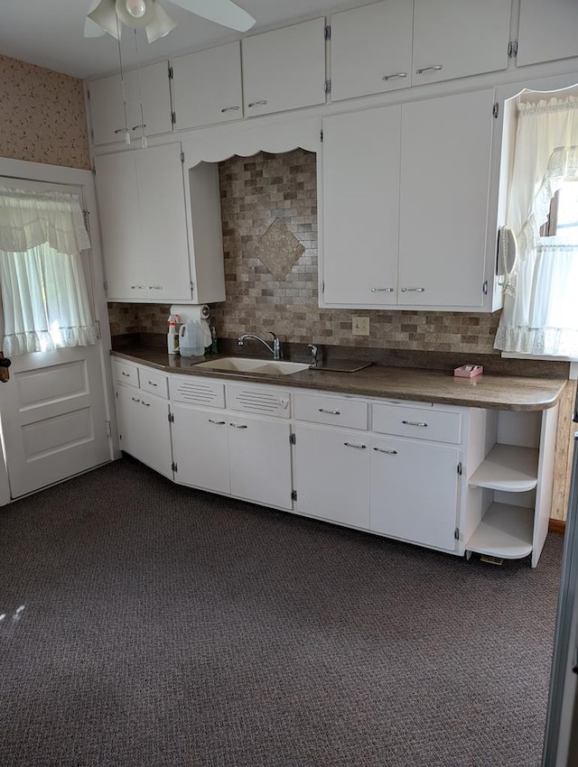 kitchen featuring white cabinets, ceiling fan, dark carpet, and sink