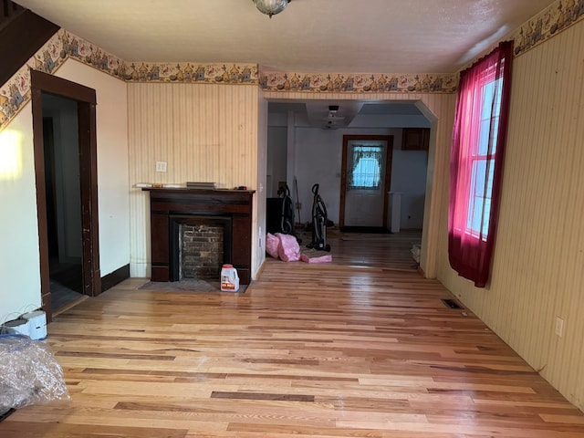 325 E Mansfield St, Bucyrus, OH 44820 - unfurnished living room with a fireplace with flush hearth, wood finished floors, wallpapered walls, and arched walkways