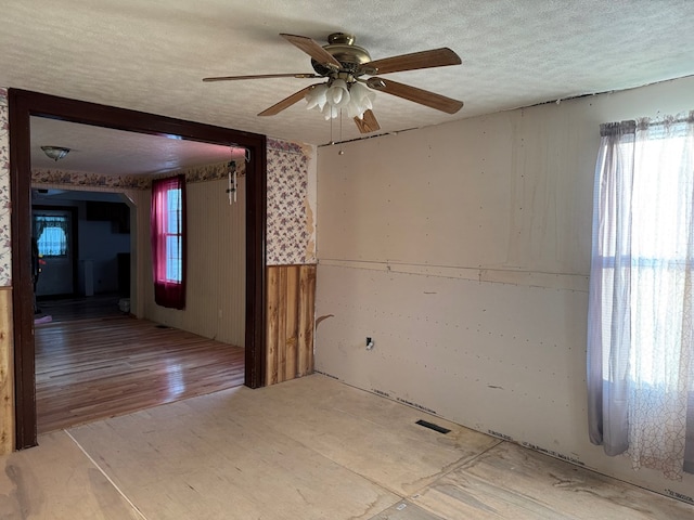 325 E Mansfield St, Bucyrus, OH 44820 - unfurnished room with ceiling fan, a textured ceiling, arched walkways, and wooden walls