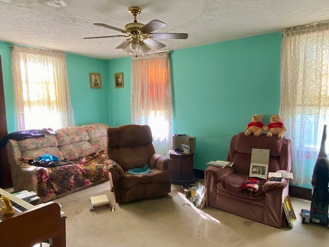 living room with carpet, ceiling fan, and a textured ceiling