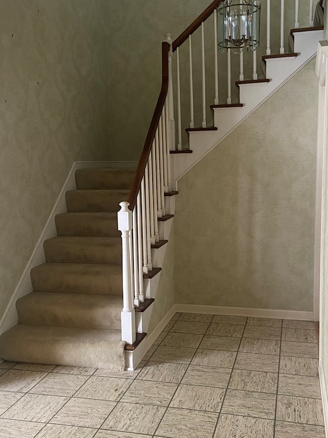 stairs featuring a notable chandelier