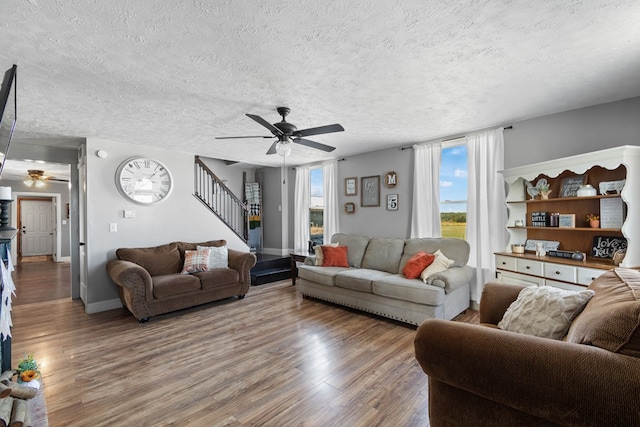 living room with ceiling fan, wood-type flooring, and a textured ceiling