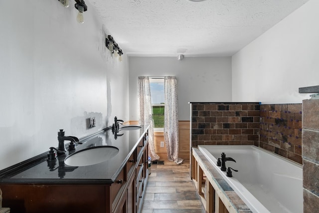 bathroom featuring a tub to relax in, vanity, a textured ceiling, and hardwood / wood-style flooring