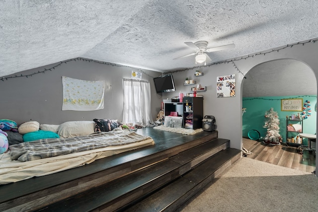 bedroom featuring a textured ceiling, ceiling fan, carpet floors, and lofted ceiling