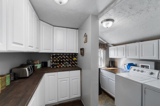 clothes washing area featuring separate washer and dryer, cabinets, and a textured ceiling