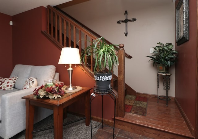 living area with baseboards, wood finished floors, and stairway