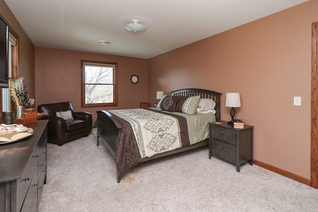 bedroom with light colored carpet and baseboards