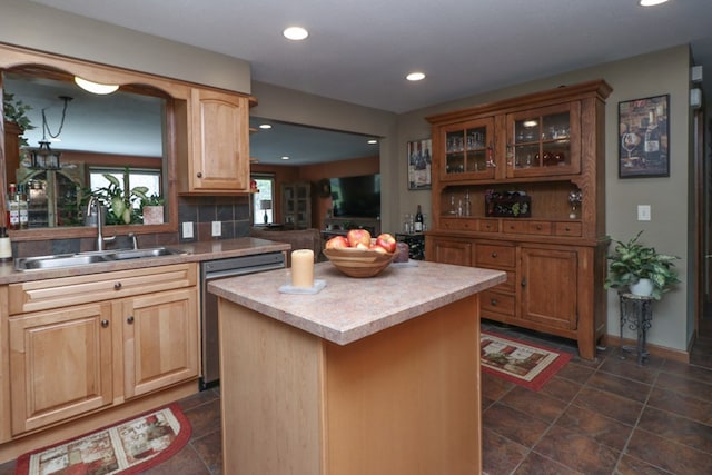 kitchen with dishwasher, tasteful backsplash, glass insert cabinets, a sink, and a center island