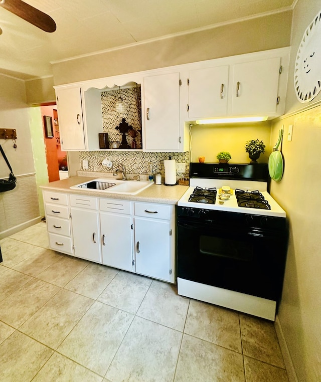 kitchen featuring sink, light tile patterned flooring, white range oven, decorative backsplash, and white cabinets