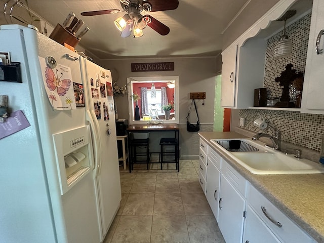 kitchen featuring sink, decorative backsplash, white fridge with ice dispenser, decorative light fixtures, and white cabinetry