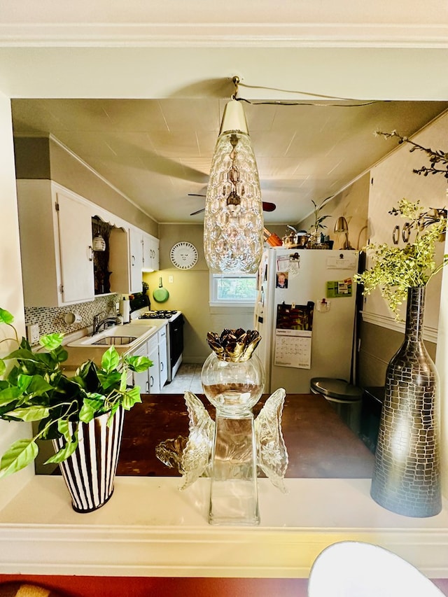 kitchen with white cabinetry, sink, pendant lighting, white appliances, and decorative backsplash