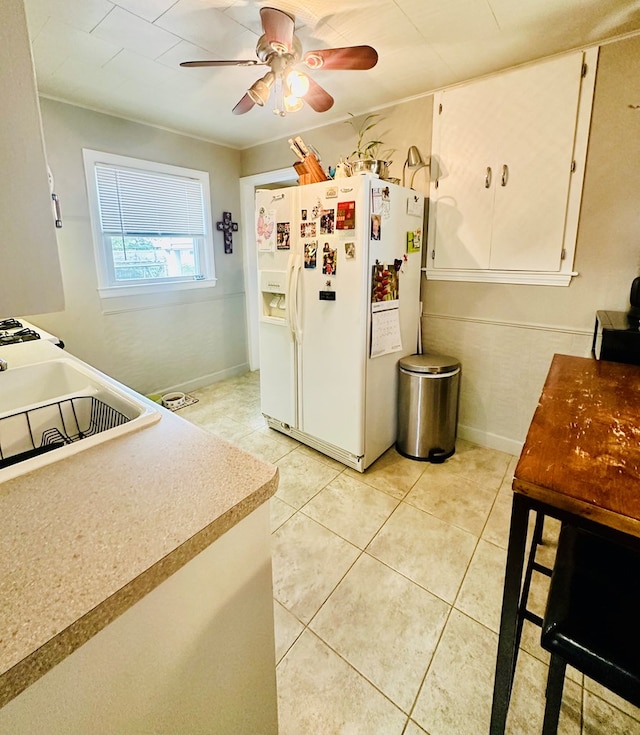 kitchen featuring ceiling fan, white fridge with ice dispenser, and light tile patterned floors