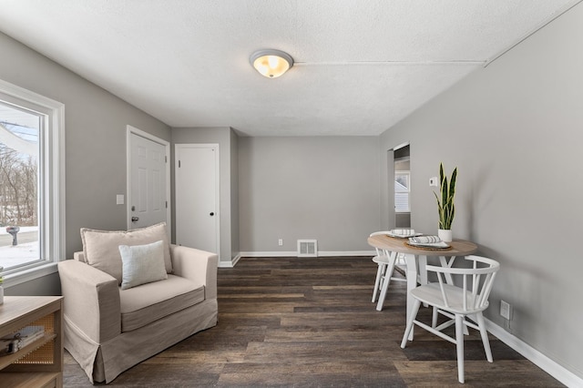 living area with a textured ceiling, a healthy amount of sunlight, and dark wood-type flooring