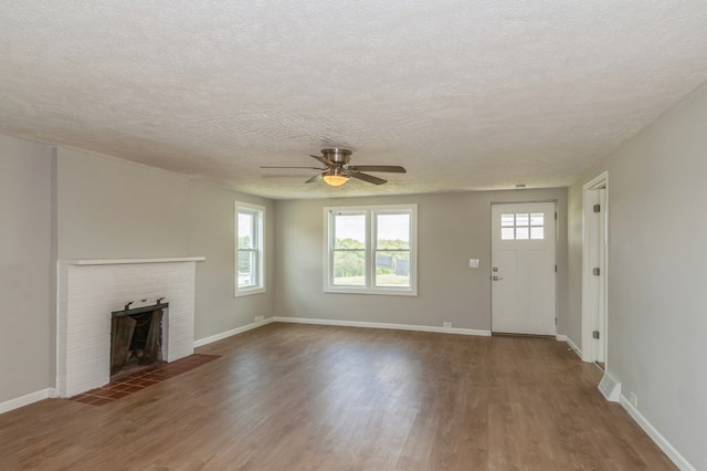 unfurnished living room featuring a fireplace, a textured ceiling, dark hardwood / wood-style flooring, and ceiling fan