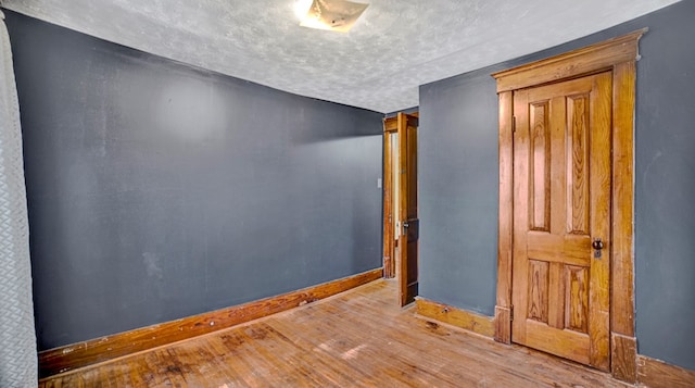 unfurnished room with a textured ceiling and light hardwood / wood-style flooring