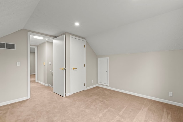 additional living space featuring light carpet, lofted ceiling, and baseboards