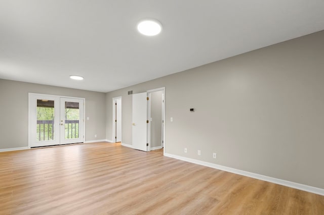 empty room featuring light wood-style floors, baseboards, and french doors