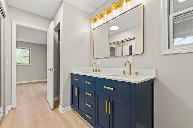 full bath featuring wood finished floors, double vanity, and baseboards