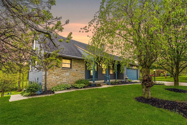 view of front of property featuring stone siding, covered porch, a front yard, and roof with shingles