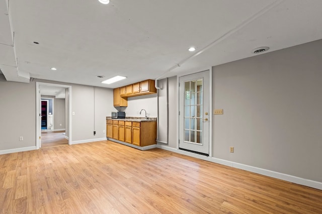kitchen featuring light wood-type flooring, baseboards, a sink, recessed lighting, and brown cabinets