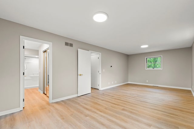 unfurnished bedroom with light wood-style floors, baseboards, and a walk in closet