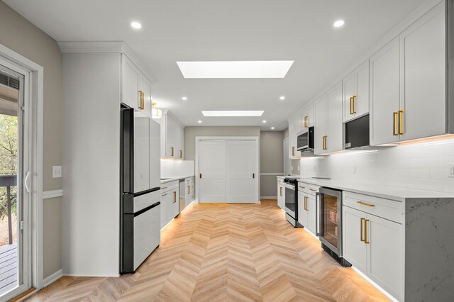 kitchen with appliances with stainless steel finishes, wine cooler, a skylight, light countertops, and recessed lighting