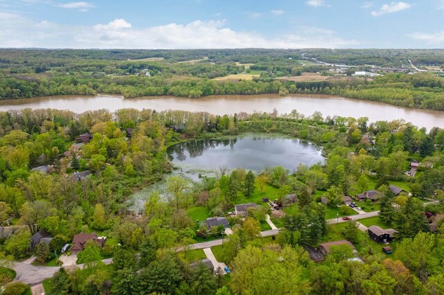aerial overview of property's location with a nearby body of water and a forest