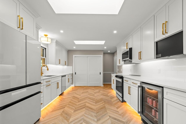 kitchen featuring beverage cooler, a skylight, recessed lighting, tasteful backsplash, and appliances with stainless steel finishes
