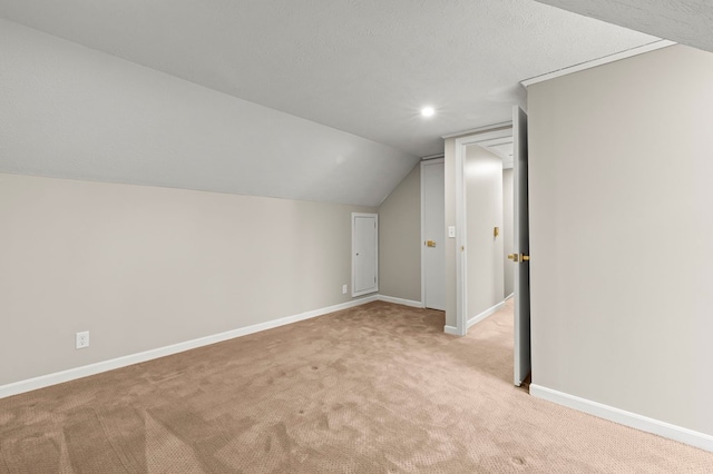 additional living space featuring light colored carpet, baseboards, and lofted ceiling
