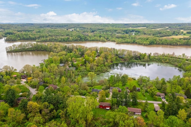 drone / aerial view of a nearby body of water and a heavily wooded area