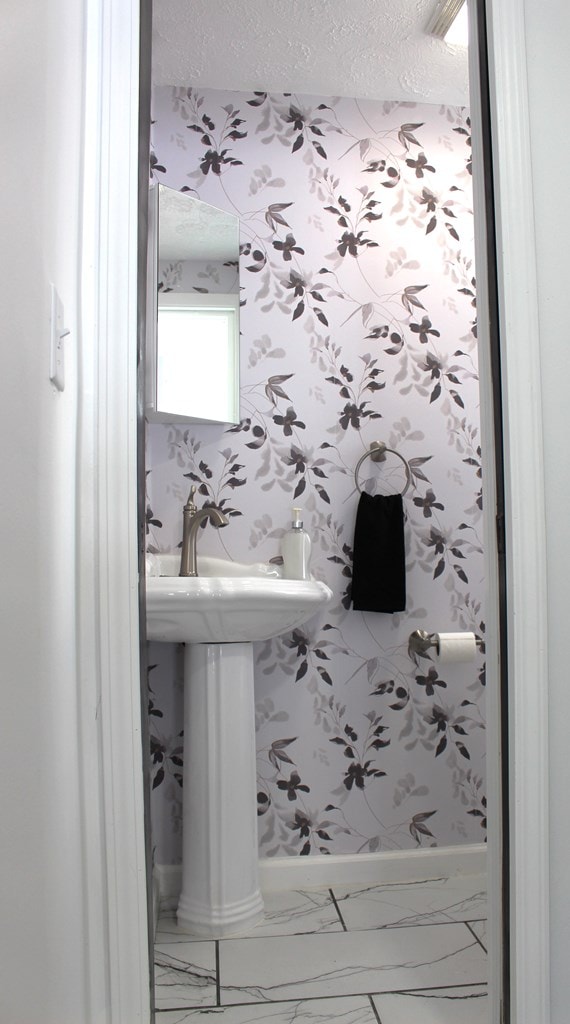 bathroom with a textured ceiling, wallpapered walls, and marble finish floor