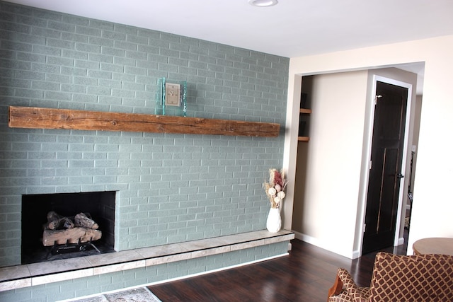 interior details featuring baseboards, a brick fireplace, and wood finished floors