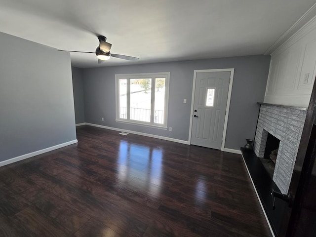 unfurnished living room featuring a brick fireplace, dark hardwood / wood-style floors, and ceiling fan