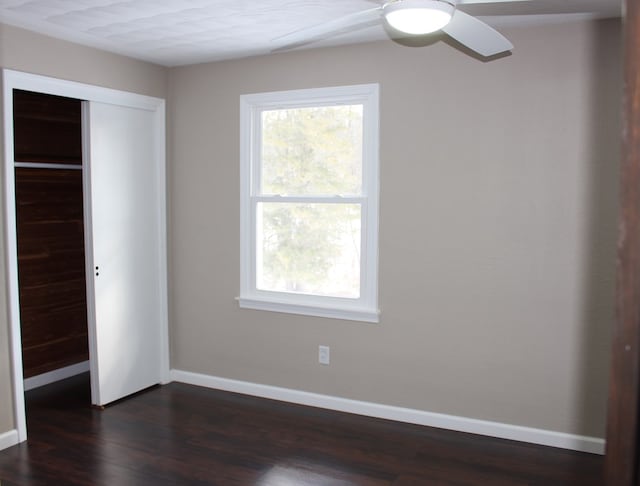 unfurnished bedroom featuring multiple windows, a closet, and dark hardwood / wood-style floors