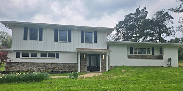 tri-level home with a front lawn and stone siding