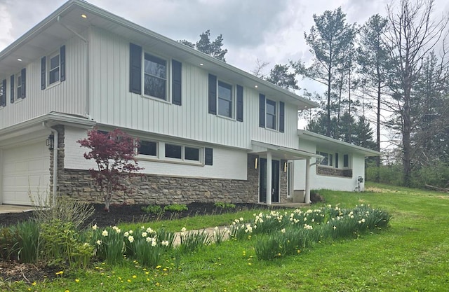 tri-level home featuring a garage, a front yard, and stone siding