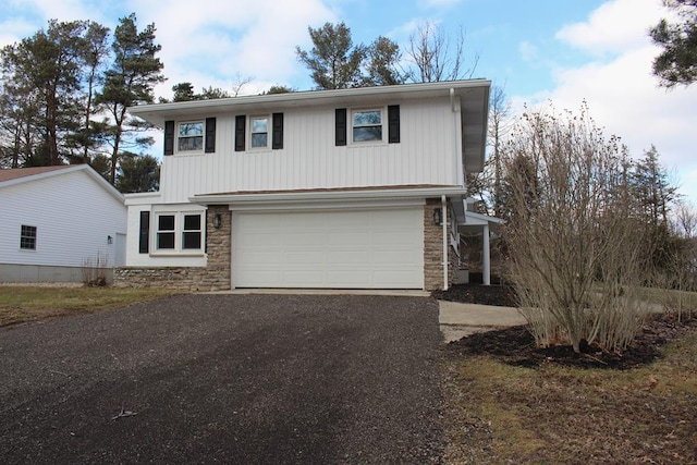 view of front facade with a garage, driveway, and stone siding